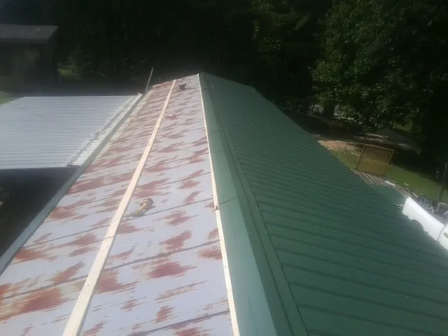 Old rusted panels beside newly installed green metal roofing — Wind Damage Roof Repair by Roofing Brothers in Pittsboro