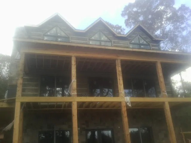 Dormers and porch framing on a large log home under construction — Roof Coating work by our crew in Pittsboro