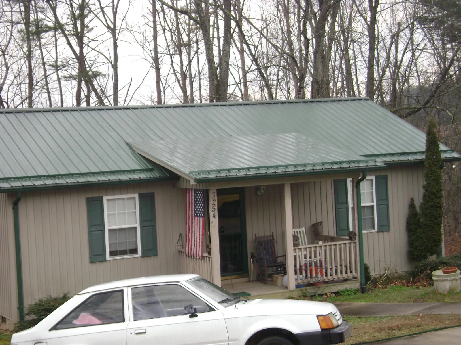 Green metal roof and front porch on a tan sided cottage in Pittsboro