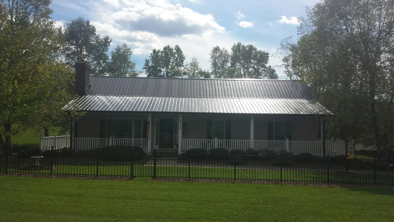 Gray metal roof on a brick ranch with a full width front porch — Gutter Guard Installation work by our crew in Pittsboro